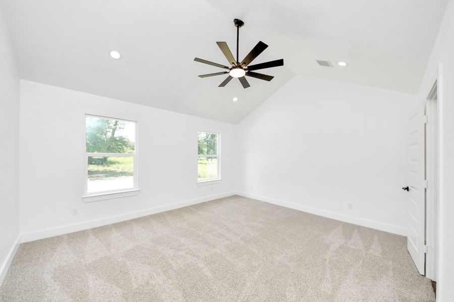 Primary bedroom with vaulted ceiling and plenty of natural sun light.