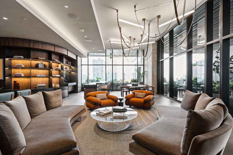 An inviting common area offers built-in shelving, ample seating, and city views through towering windows.