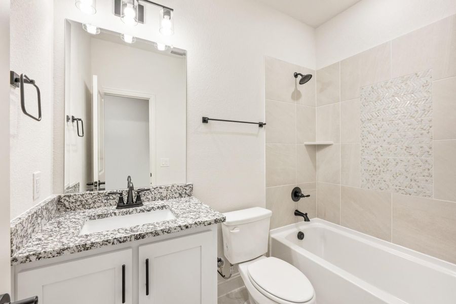 Bathroom with granite countertop vanity, white cabinets, and tiled tub-shower combo with decorative accent tile Bathroom with granite countertop vanity, white cabinets, and tiled tub-shower combo with decorative accent tile