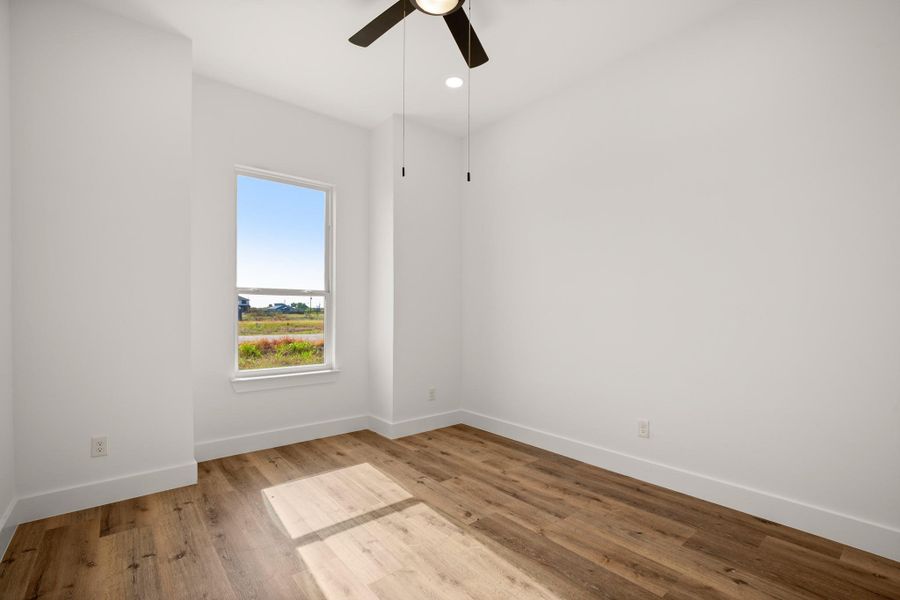 A quiet bedroom with plank flooring and a window offering views of the natural landscape. A quiet bedroom with plank flooring and a window offering views of the natural landscape.