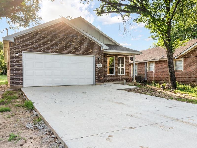 Single story home with brick siding, concrete driveway, a garage, and board and batten siding Single story home with brick siding, concrete driveway, a garage, and board and batten siding