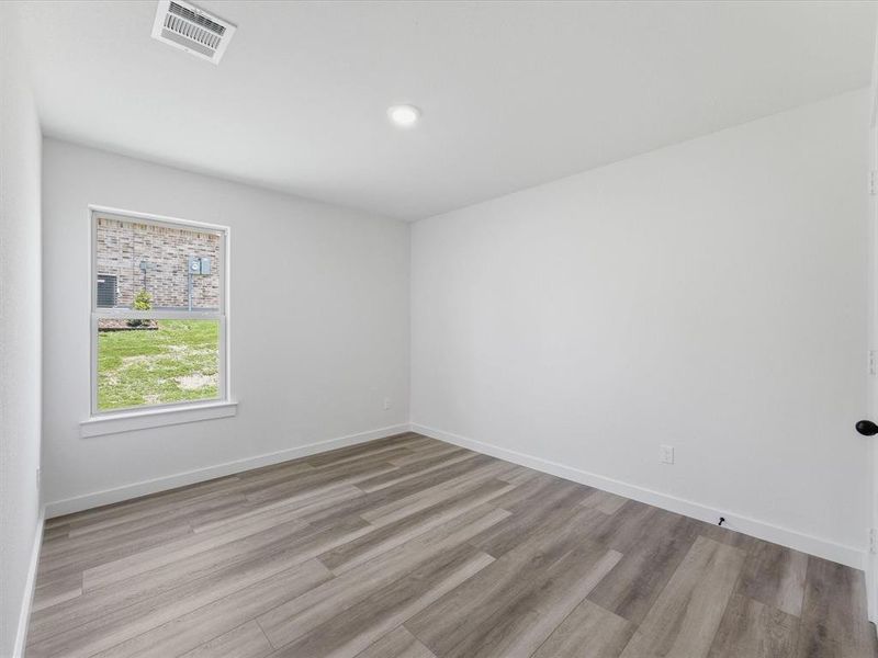 Neutral white walls with a single window, recessed lighting, and wood-finish flooring Neutral white walls with a single window, recessed lighting, and wood-finish flooring