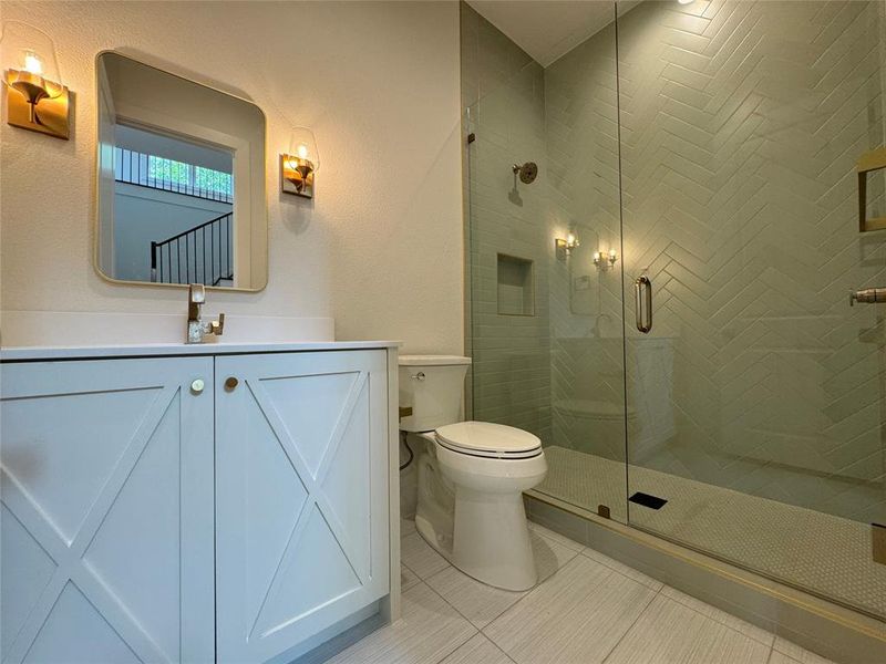 Bathroom featuring a shower with shower door, vanity, tile patterned floors, and toilet