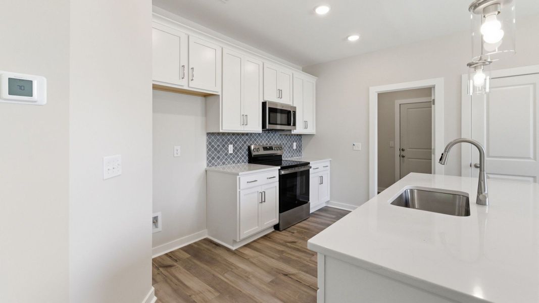 Kitchen with tile backsplash, pendant lighting, and quartz countertops