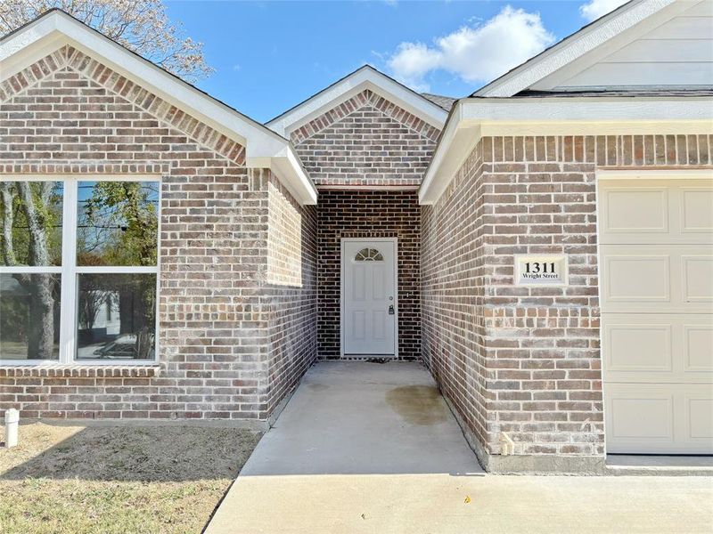 Entrance to property featuring brick siding and a garage