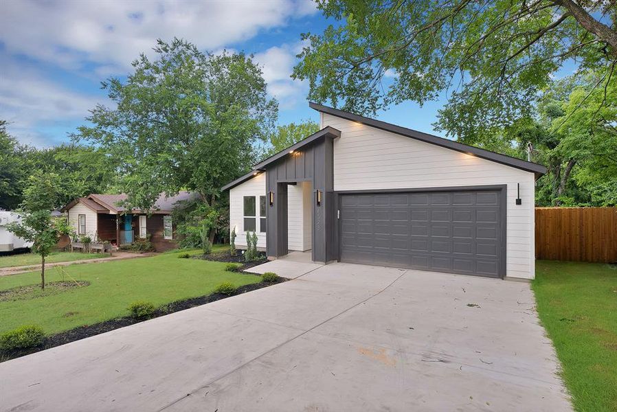 Contemporary single-story residence featuring a striking sloped roofline, white siding, and dark gray vertical panel accents Contemporary single-story residence featuring a striking sloped roofline, white siding, and dark gray vertical panel accents
