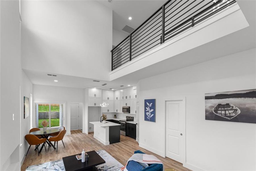 Soaring double height ceilings with open concept living, dining and kitchen - matte black railings throughout
