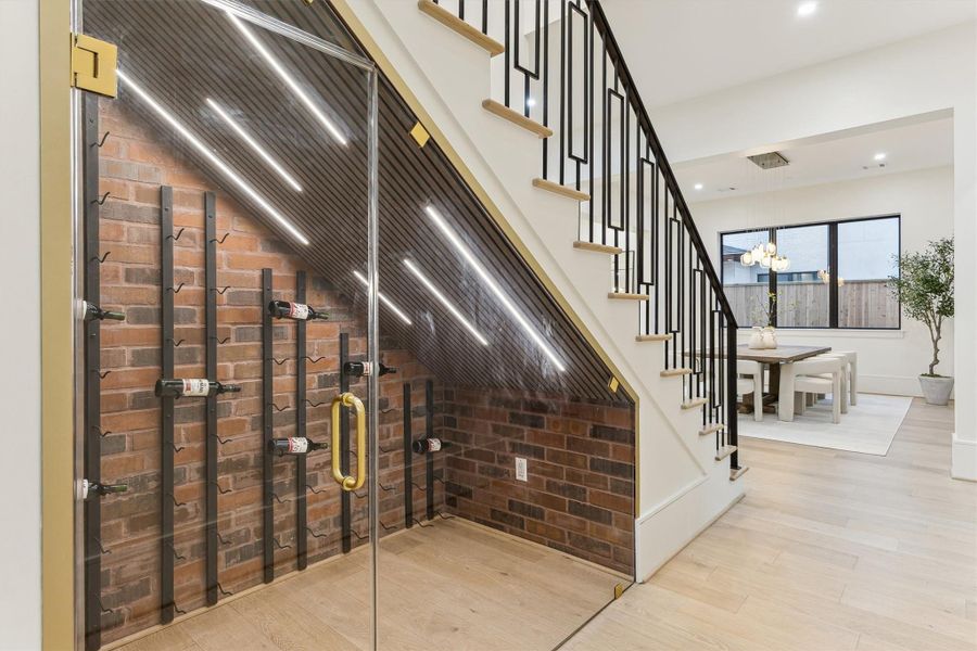 Under-stair-glass-enclosed wine cellar featuing exposed brick walls and custom metal racking.
