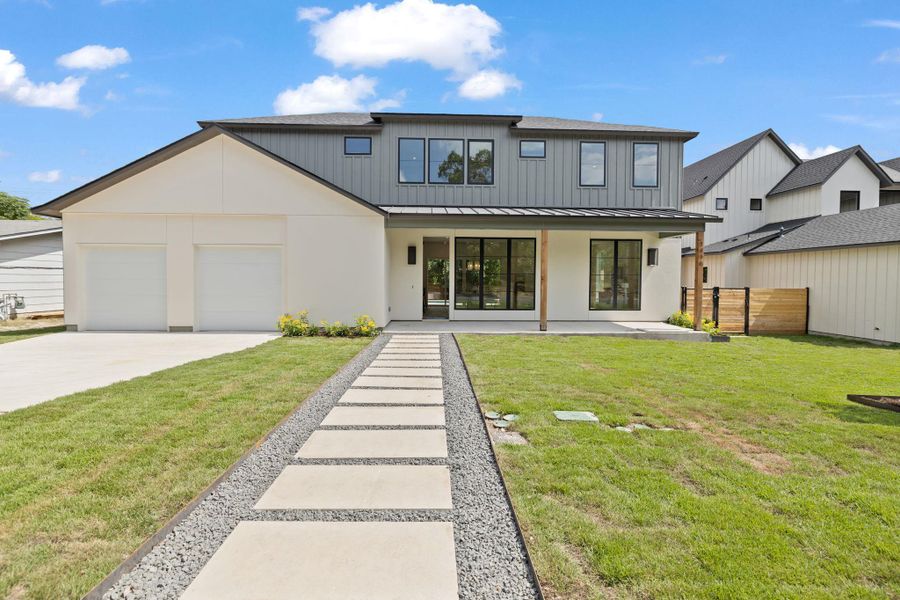 Rear view of property with concrete driveway, a garage, a metal roof, stucco siding, and a standing seam roof Rear view of property with concrete driveway, a garage, a metal roof, stucco siding, and a standing seam roof