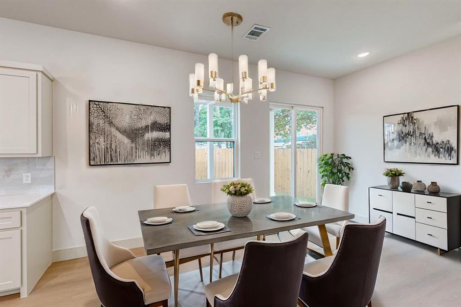 Dining area with light wood-type flooring and a notable chandelier