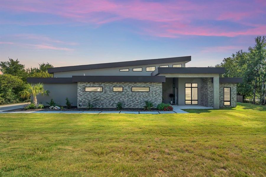Modern home with stucco siding, stone siding, and a yard