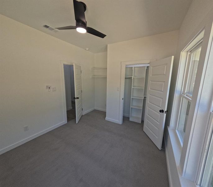 Unfurnished bedroom featuring dark carpet and ceiling fan Unfurnished bedroom featuring dark carpet and ceiling fan