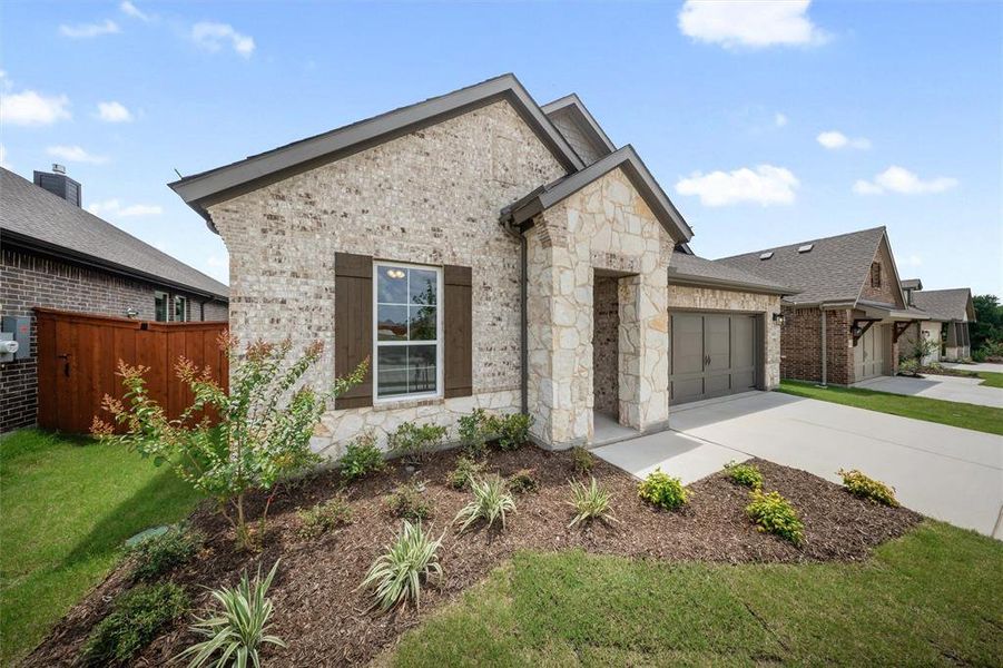 View of front of house with a garage, concrete driveway, stone siding, and brick siding