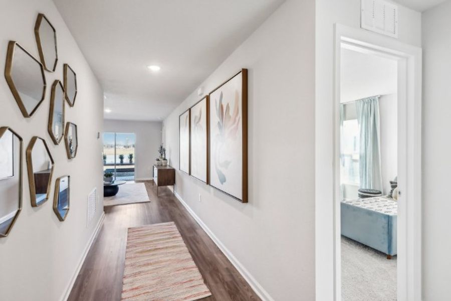 A hallway with a rug and a mirror. A hallway with a rug and a mirror.