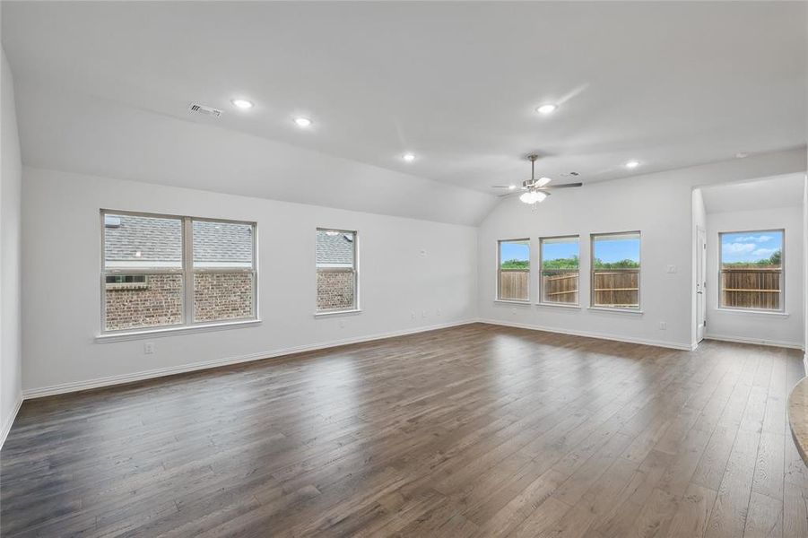 Unfurnished living room featuring dark wood-style flooring, a ceiling fan, visible vents, and baseboards Unfurnished living room featuring dark wood-style flooring, a ceiling fan, visible vents, and baseboards