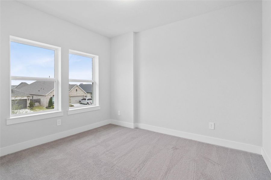 This secondary bedroom offers comfort and style with plush carpeting, neutral paint tones, recessed lighting, large windows, and a walk-in closet.