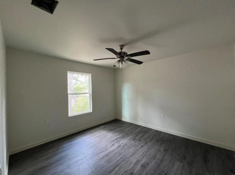 Unfurnished room with dark wood-type flooring and ceiling fan