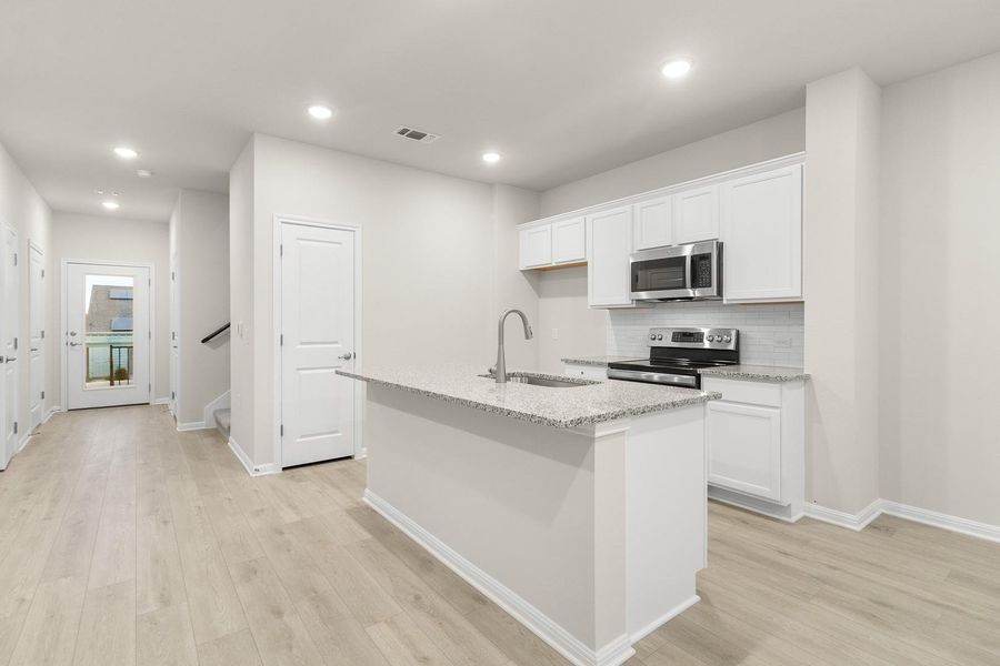 The kitchen features white cabinetry, granite countertops, and stainless steel appliances