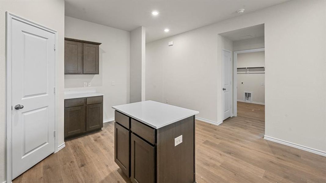 Kitchen with dark wood finish cabinetry, a kitchen island, light wood-type flooring, and recessed lighting