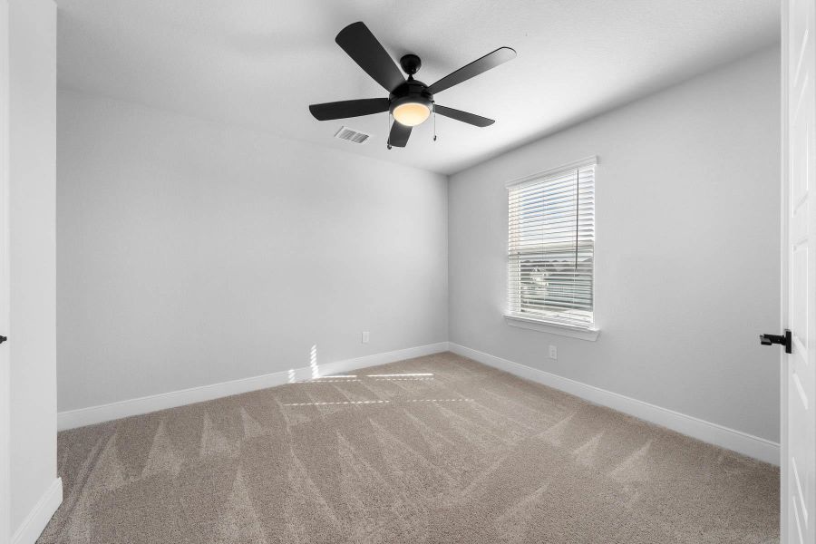 Carpeted spare room with baseboards and ceiling fan