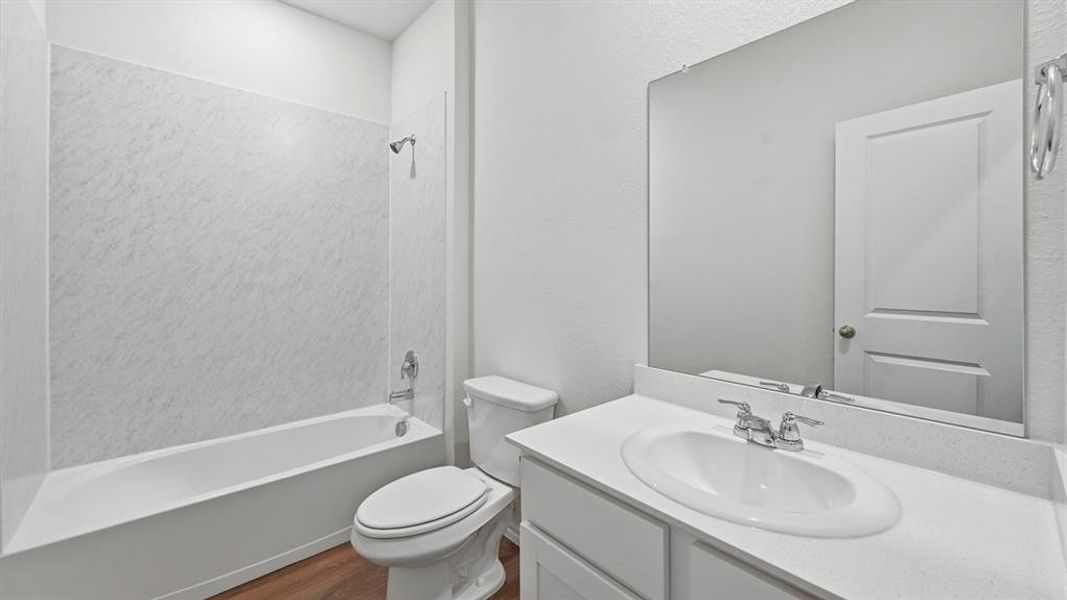 Bathroom featuring shower / tub combination, vanity, and dark wood-style flooring