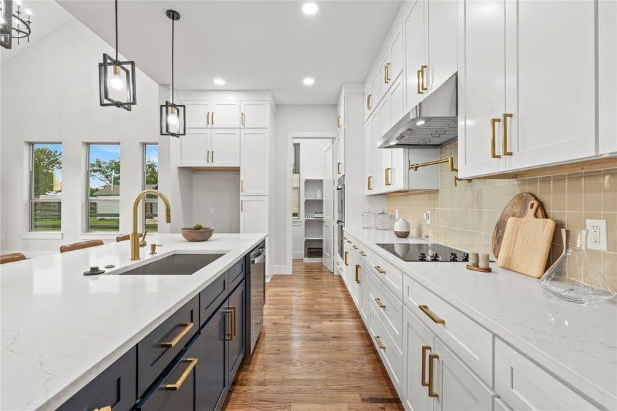 Kitchen with range hood, white cabinetry, appliances with stainless steel finishes, light wood-style floors, and recessed lighting Kitchen with range hood, white cabinetry, appliances with stainless steel finishes, light wood-style floors, and recessed lighting