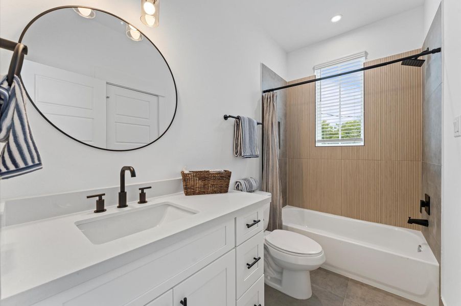 This secondary bathroom on the second floor is designed to serve two adjacent bedrooms with both style and functionality. It offers ample space for shared use, while the tub-shower combo provides versatility for quick rinses or relaxing soaks. The space is elevated by contemporary finishes and sleek tilework, creating a clean, modern aesthetic that feels both fresh and refined.