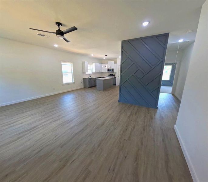 Unfurnished living room with dark wood-style floors, ceiling fan, a barn door, and recessed lighting Unfurnished living room with dark wood-style floors, ceiling fan, a barn door, and recessed lighting