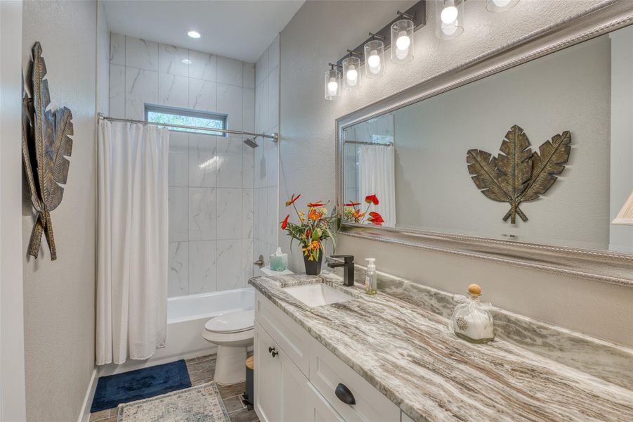 Full bathroom featuring a textured wall, vanity, and shower / bathtub combination with curtain