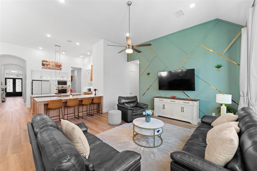 Living area with arched walkways, light wood-type flooring, recessed lighting, an accent wall, and a ceiling fan Living area with arched walkways, light wood-type flooring, recessed lighting, an accent wall, and a ceiling fan