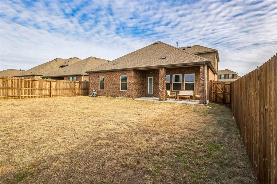 Back of house with a lawn and a patio