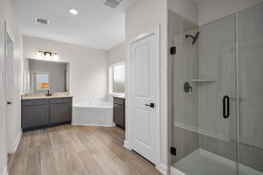 The luxurious master bathroom features corner soaking tub, large walk-in shower, separate vanities, and lots of storage.