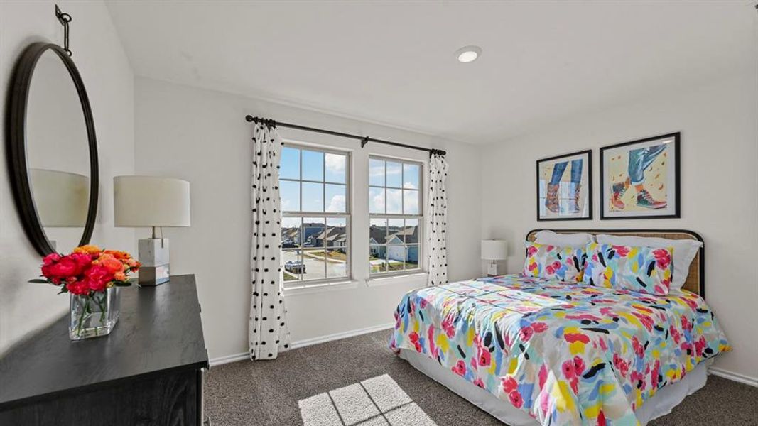 This room features light-colored walls, carpeted flooring, and two windows providing natural light This room features light-colored walls, carpeted flooring, and two windows providing natural light