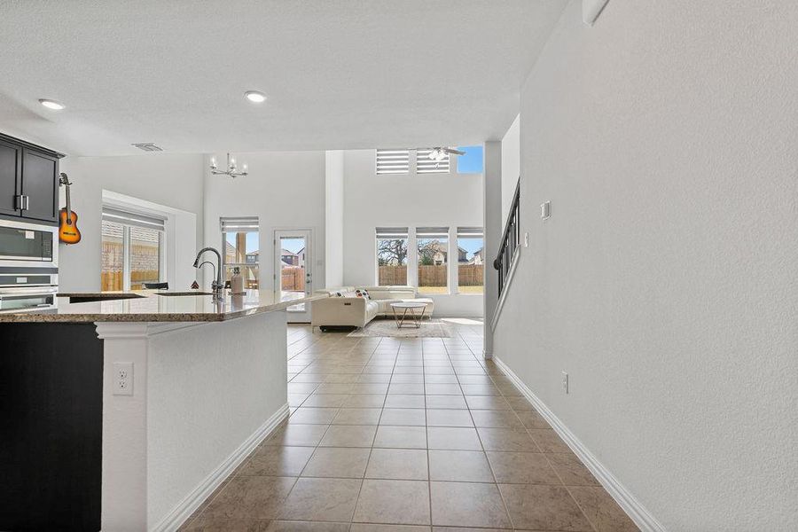 Kitchen with light stone countertops, plenty of natural light, open floor plan, stainless steel appliances, and a high ceiling Kitchen with light stone countertops, plenty of natural light, open floor plan, stainless steel appliances, and a high ceiling