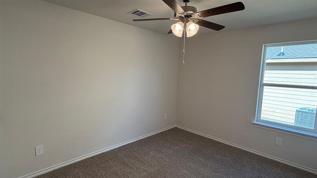 Carpeted room featuring a ceiling fan with integrated lighting, a double-pane window, and light-toned walls
