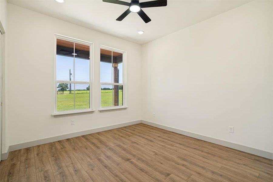 bedroom 2 featuring wood-finish flooring, two large windows, recessed ceiling lighting, and a ceiling fan