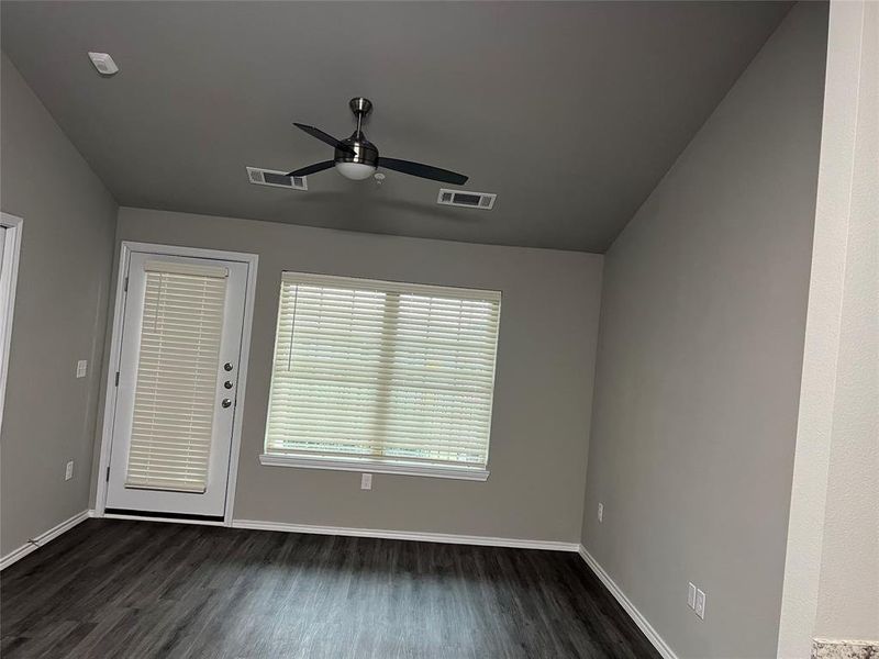 Empty room featuring a ceiling fan, dark wood finished floors, baseboards, and vaulted ceiling