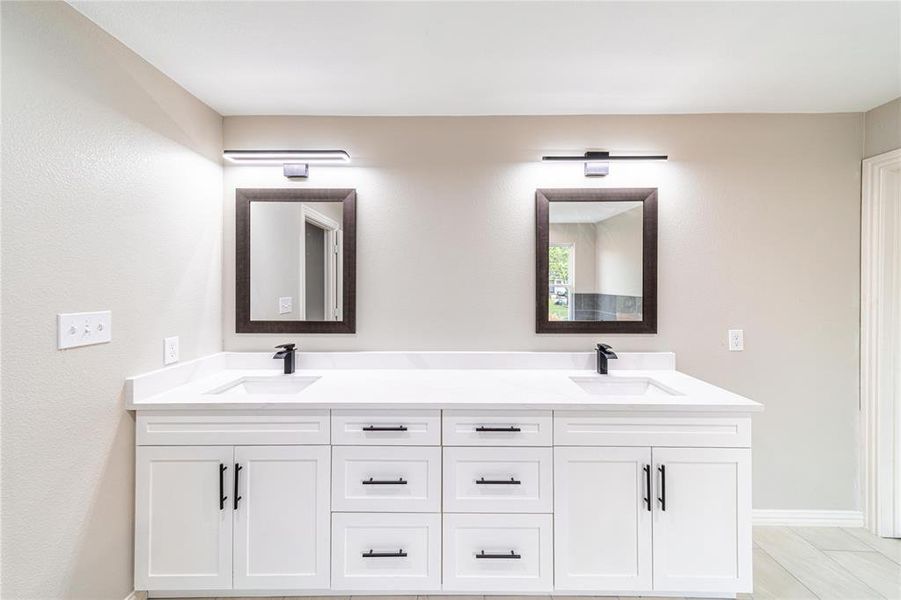 Full bath featuring double vanity and baseboards