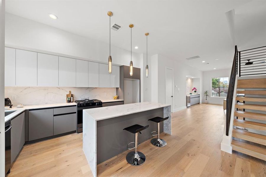 This elegant kitchen features sophisticated European-style cabinets with sleek, minimalist lines paired with stunning quartz countertops for a modern luxury and timeless appeal.