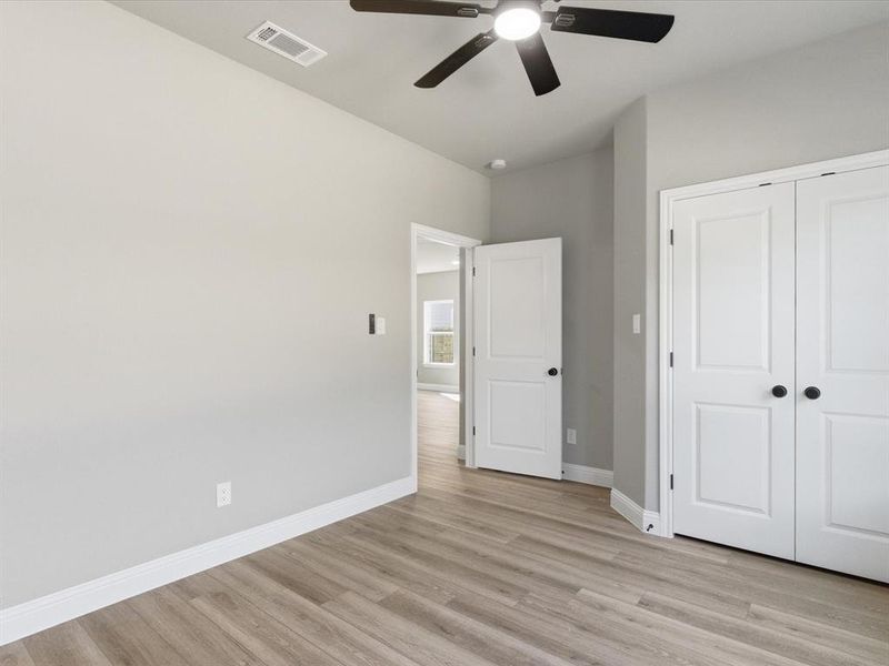 Unfurnished bedroom with light wood-style flooring, ceiling fan, and a closet Unfurnished bedroom with light wood-style flooring, ceiling fan, and a closet