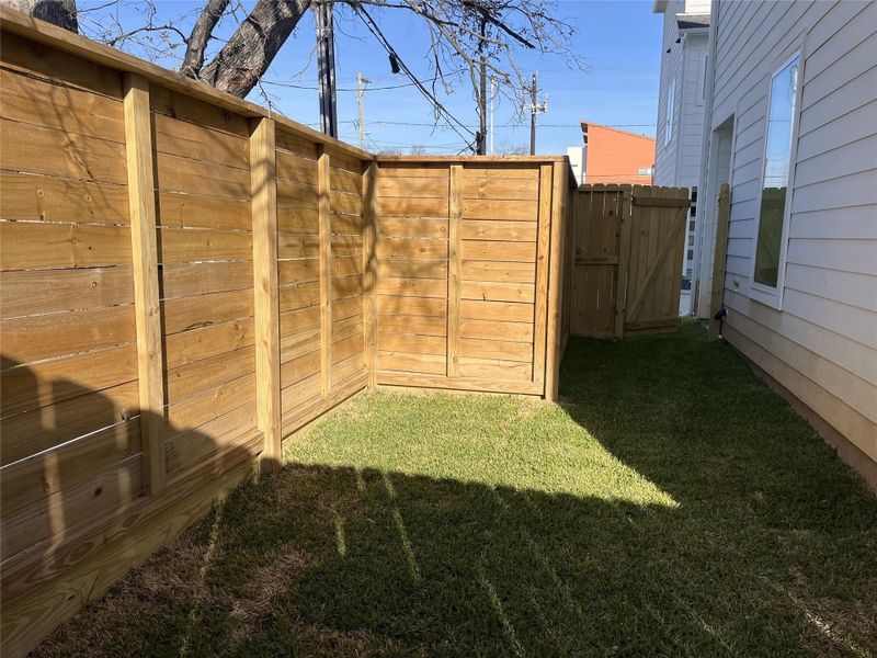This cozy side yard/backyard patio offers a charming outdoor retreat, accessible directly from the secondary bedroom and through a wooden gate that leads to the driveway, providing convenient indoor-outdoor flow and added privacy.