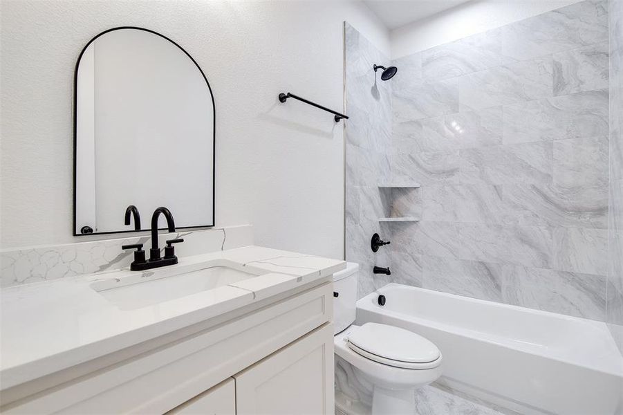 Full bathroom with vanity, tiled shower / bath combo, and toilet