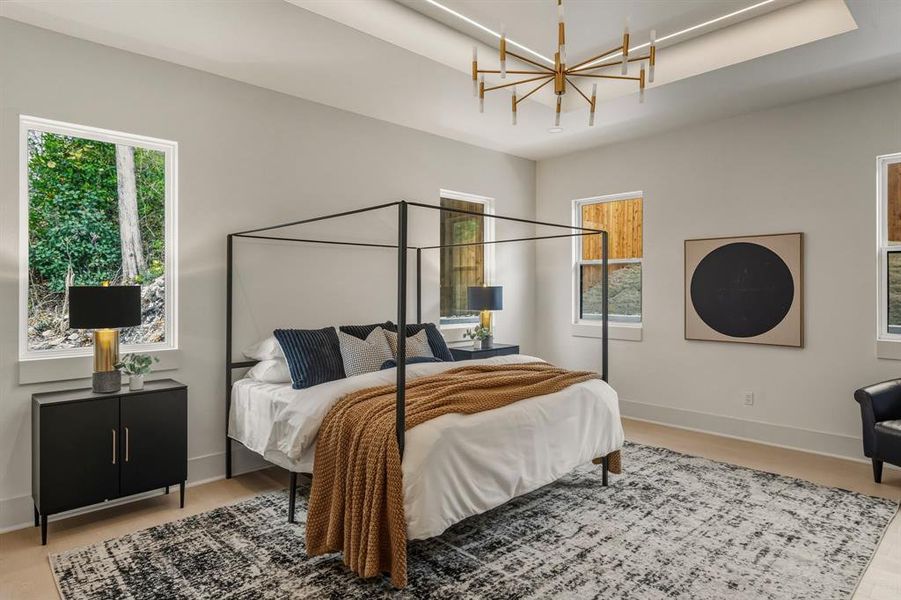 Bedroom with a raised ceiling, wood finished floors, and a chandelier