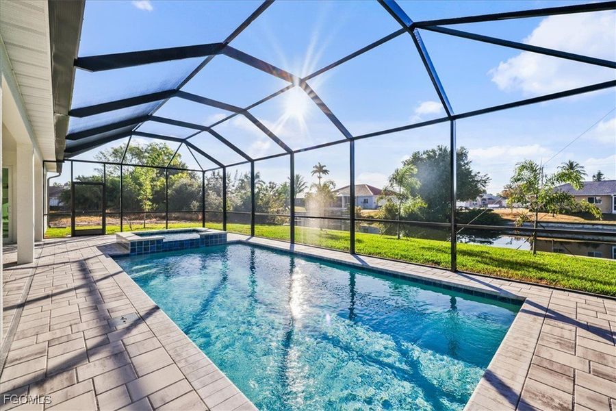 View of pool with a sunroom, glass enclosure, a pool with connected hot tub, a patio, and a yard