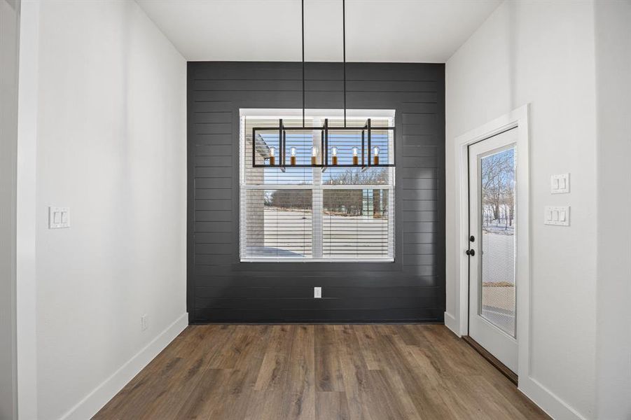 Unfurnished dining area featuring baseboards and dark wood finished floors