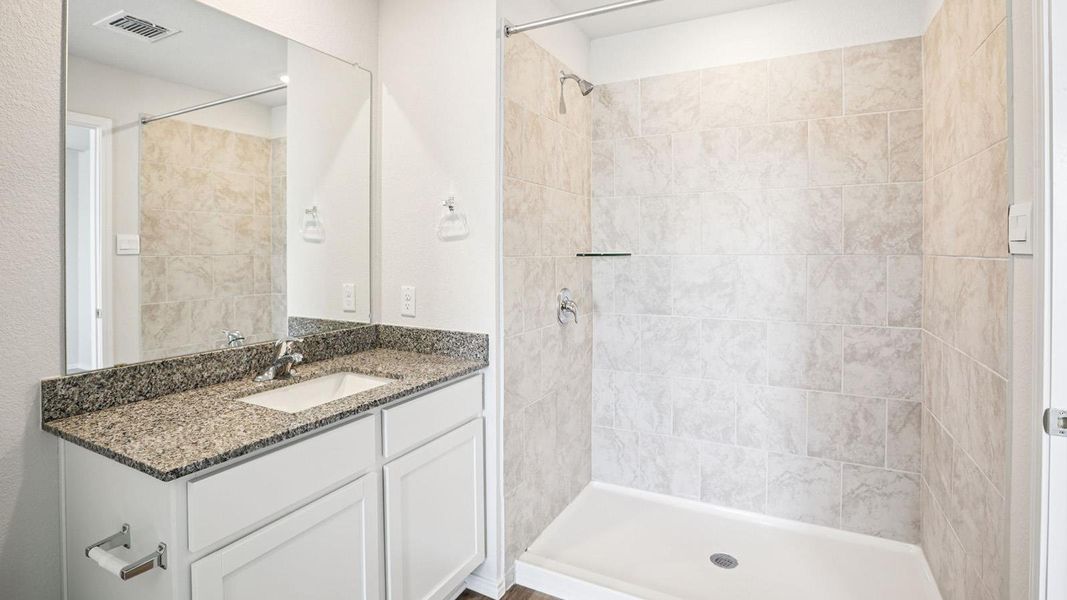 Bathroom featuring a single vanity with a granite countertop, undermount sink, and a large wall-mounted mirror
