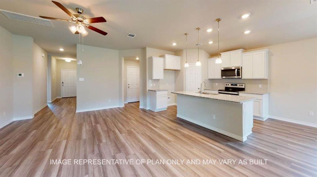 Kitchen with a center island with sink, white cabinetry, hanging light fixtures, open floor plan, and appliances with stainless steel finishes Kitchen with a center island with sink, white cabinetry, hanging light fixtures, open floor plan, and appliances with stainless steel finishes