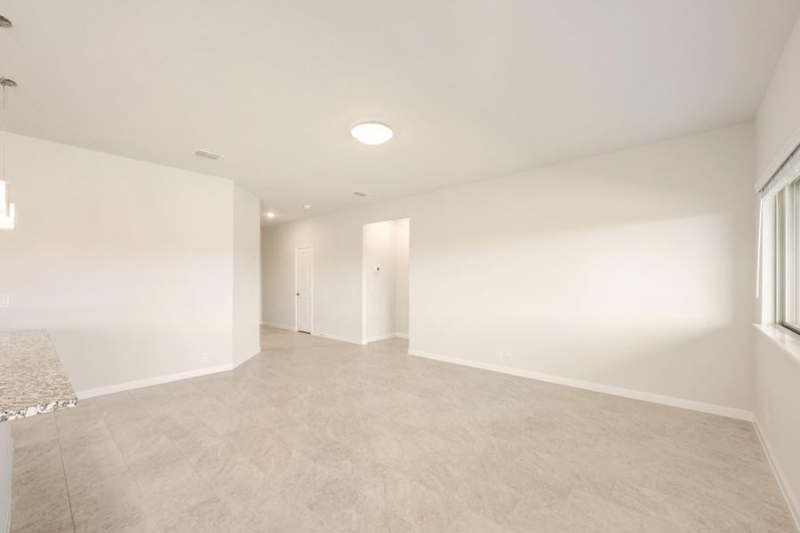Empty living area with white walls, tile floors, and a window with natural light
