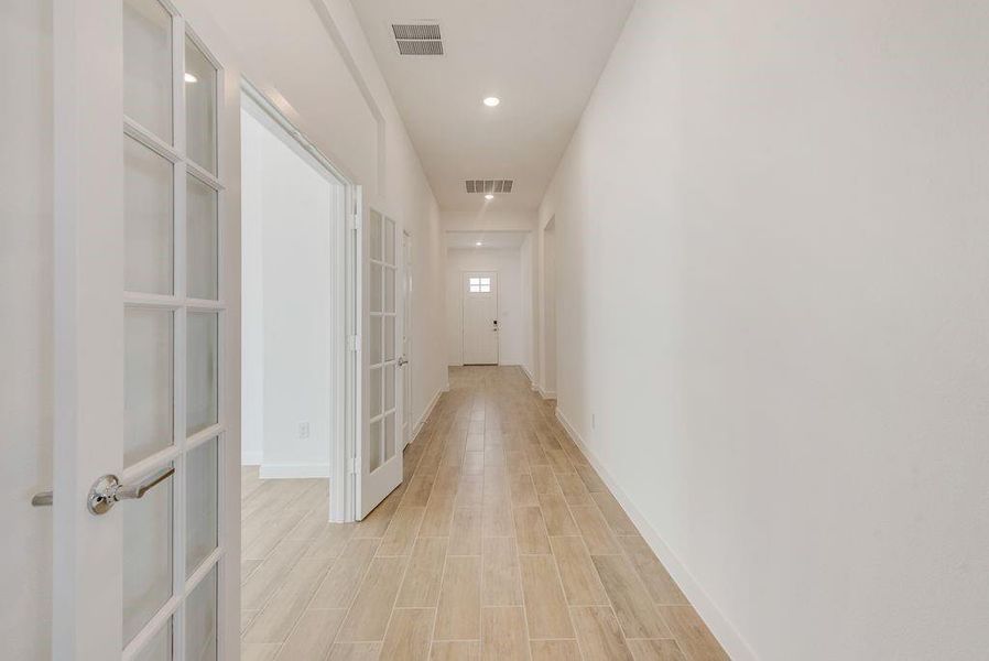 Hallway with french doors, light wood-style floors, and recessed lighting