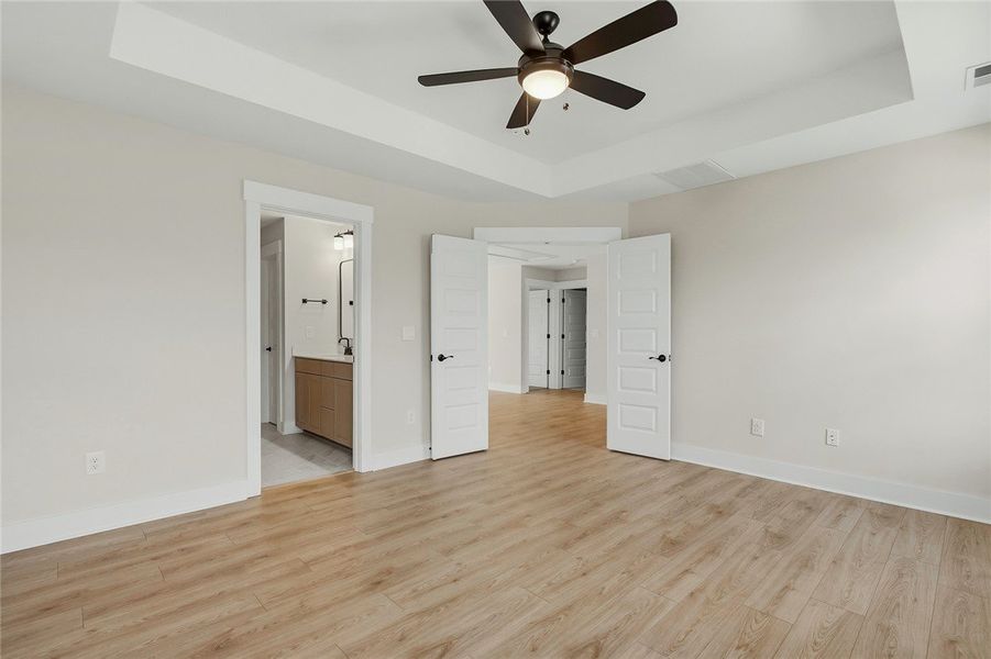 Warm wood flooring and an elegant tray ceiling def